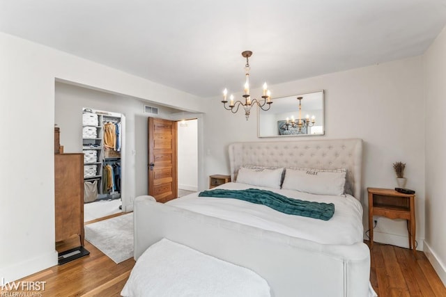 bedroom with an inviting chandelier, baseboards, and wood finished floors