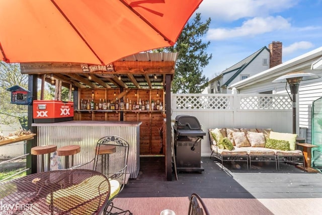 view of patio / terrace featuring area for grilling, a deck, fence, and outdoor dry bar