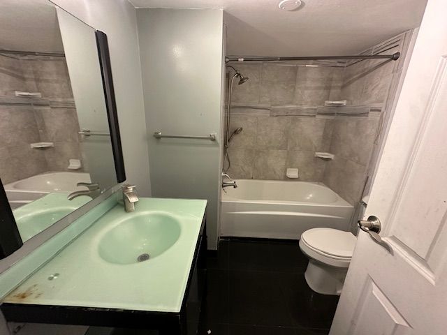 full bathroom featuring toilet, washtub / shower combination, tile patterned flooring, and vanity