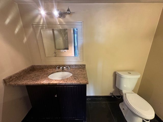bathroom with toilet, baseboards, tile patterned flooring, and vanity
