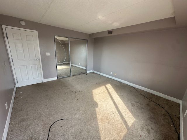 unfurnished bedroom featuring visible vents, baseboards, carpet floors, and a closet