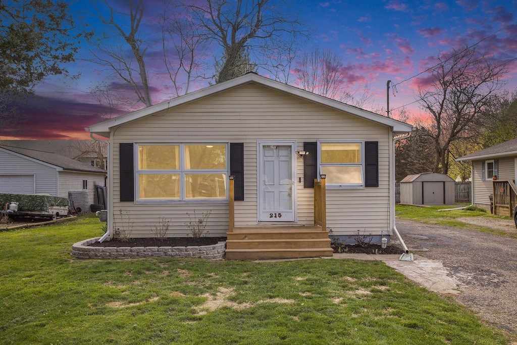 bungalow-style home featuring a storage shed, an outdoor structure, and a front lawn