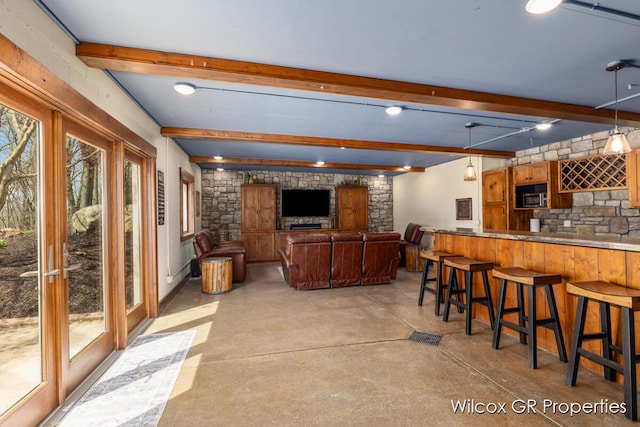 interior space with stainless steel microwave, concrete floors, beam ceiling, and wet bar