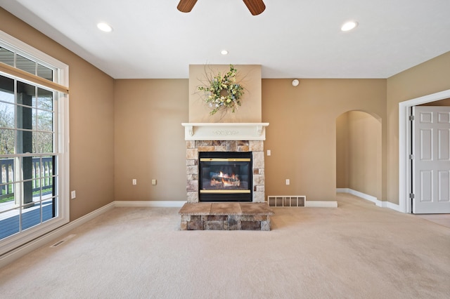 unfurnished living room with carpet floors, arched walkways, visible vents, and a fireplace