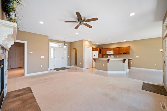 unfurnished living room featuring light colored carpet, a ceiling fan, recessed lighting, and a fireplace