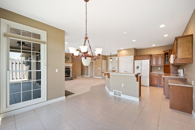 kitchen featuring brown cabinetry, visible vents, light countertops, white appliances, and light tile patterned flooring