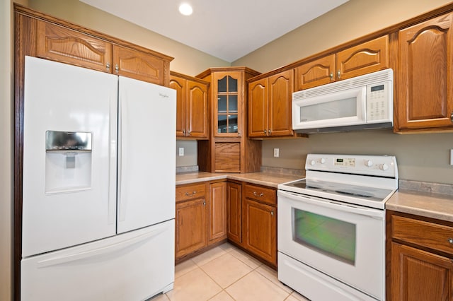 kitchen featuring brown cabinetry, light countertops, and white appliances