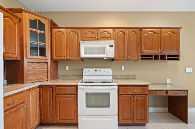 kitchen featuring light tile patterned floors, light countertops, brown cabinetry, and white appliances