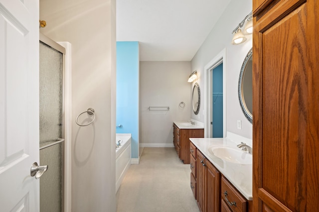 full bathroom with baseboards, two vanities, a sink, and a stall shower