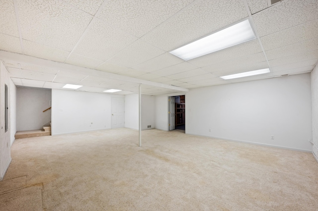 finished below grade area featuring carpet flooring, stairs, and a paneled ceiling