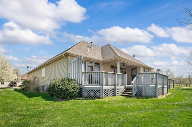 rear view of property featuring ceiling fan, a yard, and central AC