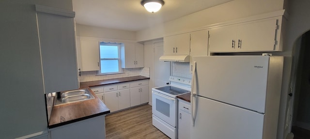kitchen featuring dark countertops, white appliances, under cabinet range hood, a sink, and backsplash