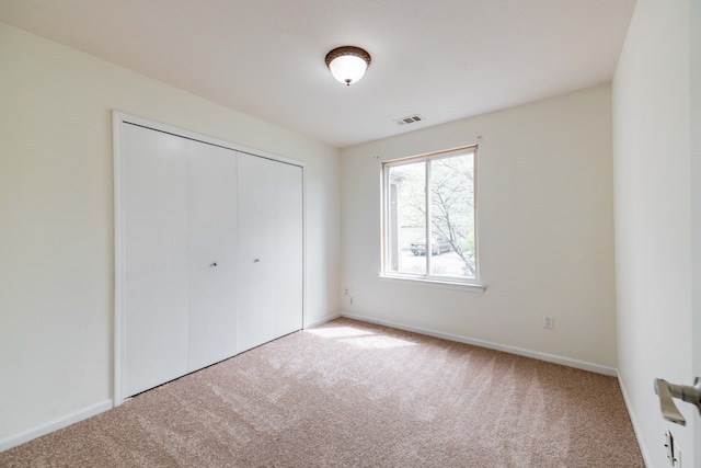 unfurnished bedroom featuring baseboards, visible vents, carpet, and a closet