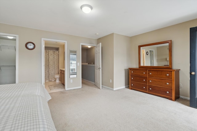 bedroom with baseboards, light carpet, a closet, and a walk in closet