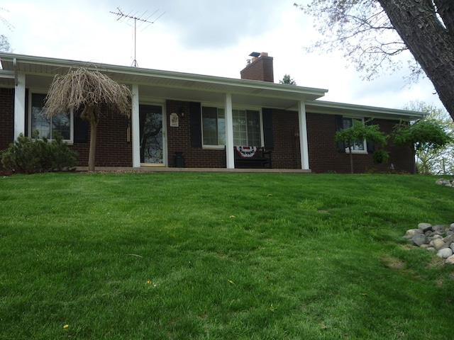 back of house featuring brick siding, a yard, a chimney, and a porch