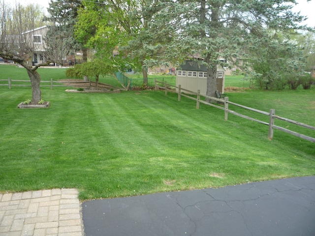 view of yard featuring a storage shed, fence, and an outdoor structure