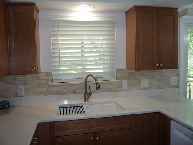 kitchen with a sink, a wealth of natural light, white dishwasher, and tasteful backsplash