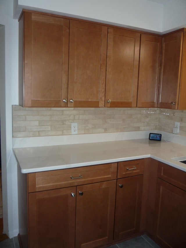kitchen with brown cabinetry, light countertops, and tasteful backsplash