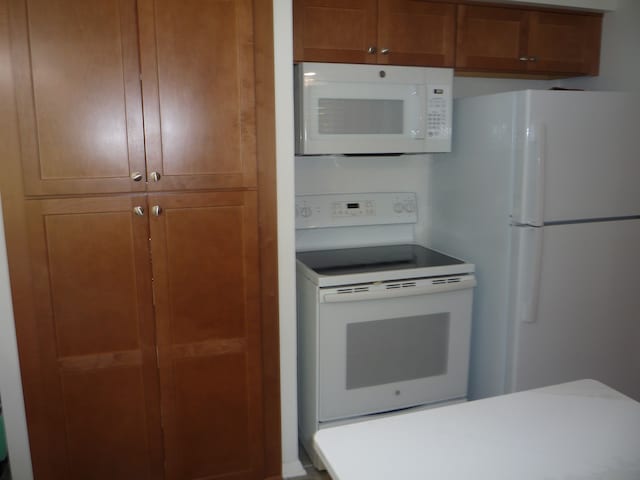 kitchen featuring brown cabinets and white appliances