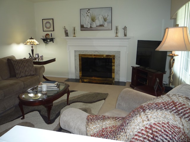 living room with baseboards, a high end fireplace, and carpet