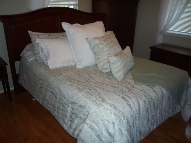 bedroom with multiple windows and wood finished floors