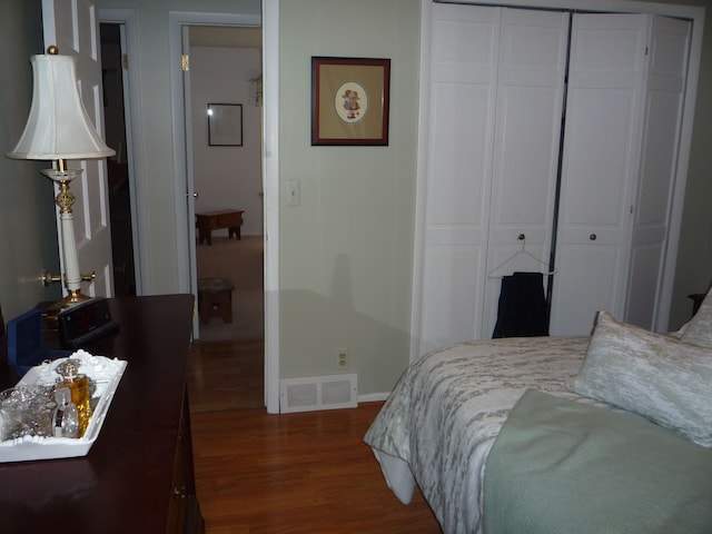 bedroom with baseboards, visible vents, a closet, and dark wood-type flooring