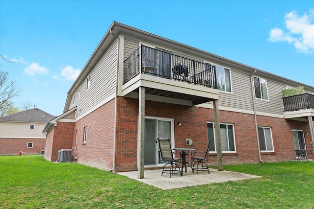 rear view of property with a yard, a patio area, brick siding, and a balcony