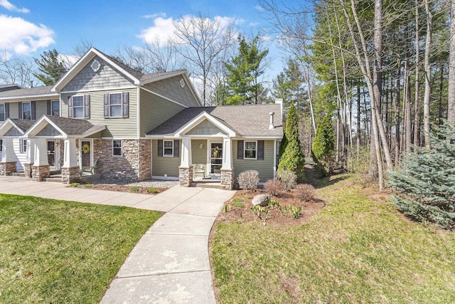 craftsman house with a porch, a shingled roof, a front lawn, and stone siding