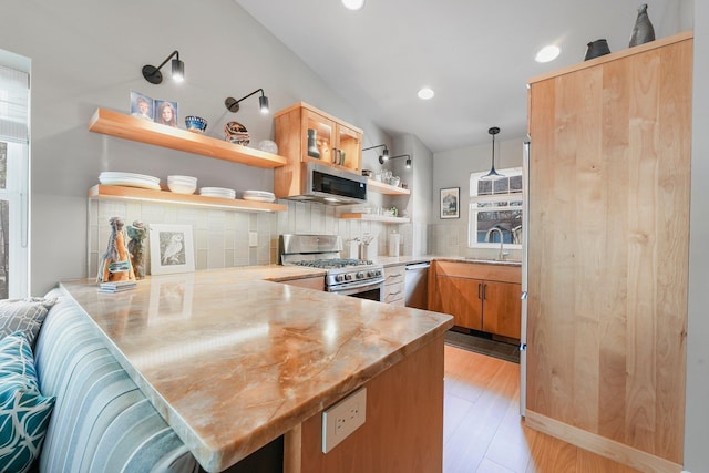 kitchen with appliances with stainless steel finishes, tasteful backsplash, open shelves, a sink, and a peninsula