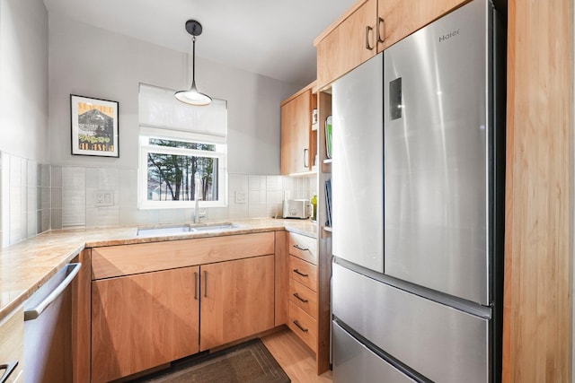 kitchen featuring backsplash, hanging light fixtures, a sink, light countertops, and stainless steel appliances