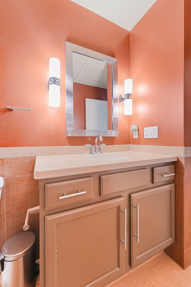 half bath with toilet, tile walls, and vanity