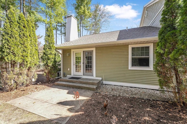 exterior space featuring roof with shingles and a chimney