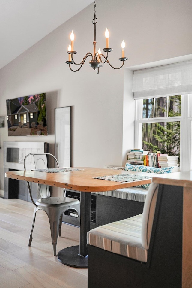 dining room featuring a chandelier, wood finished floors, and vaulted ceiling
