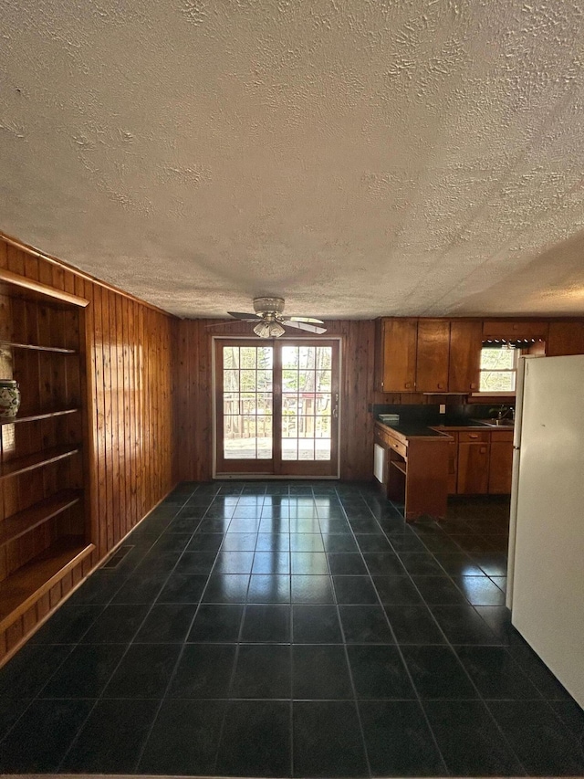 757 E Sidney Rd, Stanton, MI 48888 - interior space with wooden walls, dark tile patterned floors, a ceiling fan, and brown cabinets