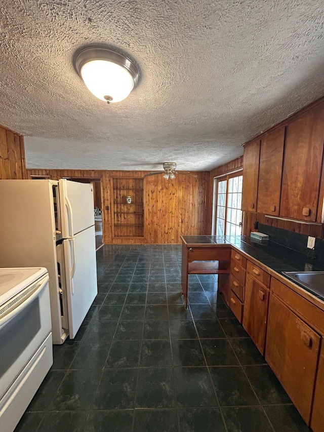 757 E Sidney Rd, Stanton, MI 48888 - kitchen featuring wood walls, white appliances, brown cabinets, dark tile patterned flooring, and a sink
