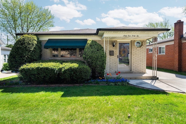 view of front of property featuring a porch, brick siding, and a front lawn