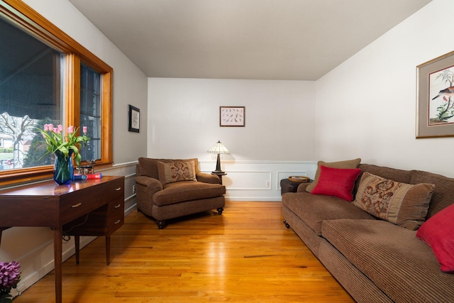 living area featuring light wood-style flooring and a wainscoted wall