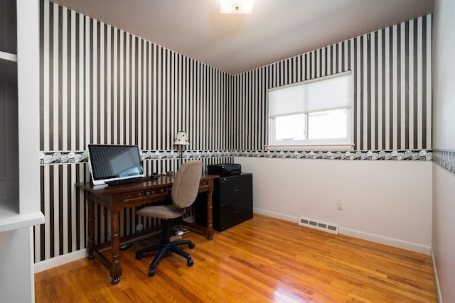 home office featuring wallpapered walls, visible vents, baseboards, and wood finished floors