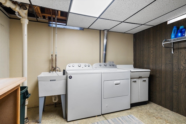 washroom featuring wooden walls, laundry area, a sink, and washer and dryer