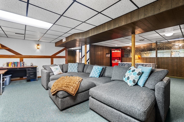 living area with carpet flooring, a paneled ceiling, and wooden walls