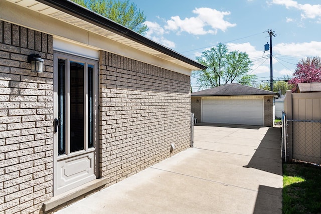 view of home's exterior with brick siding, a garage, fence, and an outdoor structure