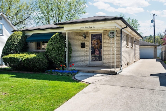 view of front of house featuring a front lawn, brick siding, a porch, an outbuilding, and a detached garage
