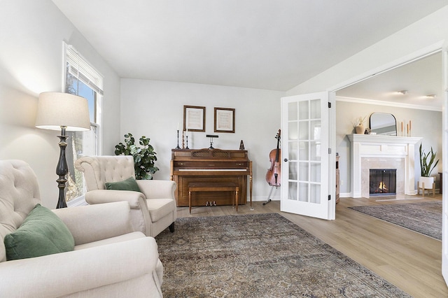 living area featuring baseboards, a warm lit fireplace, and wood finished floors