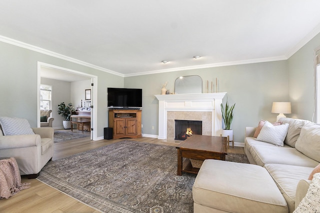 living room featuring baseboards, ornamental molding, light wood finished floors, and a fireplace
