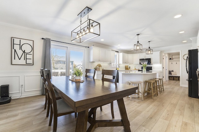 dining room with crown molding, recessed lighting, and light wood-style flooring