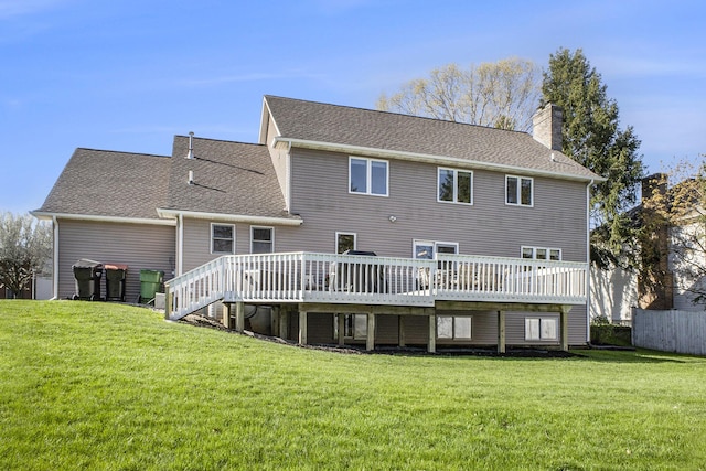 rear view of property with a shingled roof, a wooden deck, a yard, and a chimney