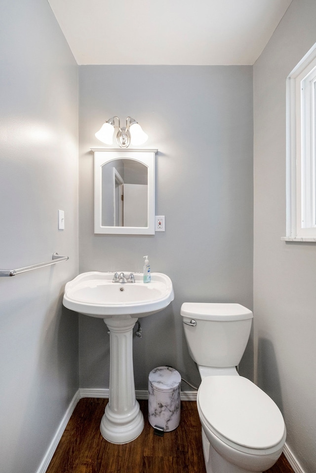half bathroom featuring baseboards, toilet, and wood finished floors