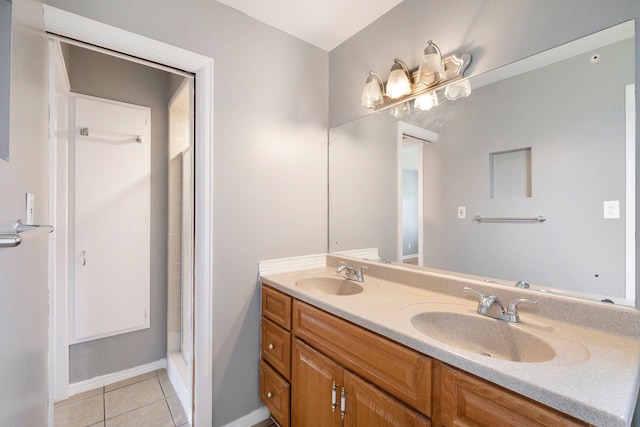 bathroom with double vanity, a sink, baseboards, and tile patterned floors