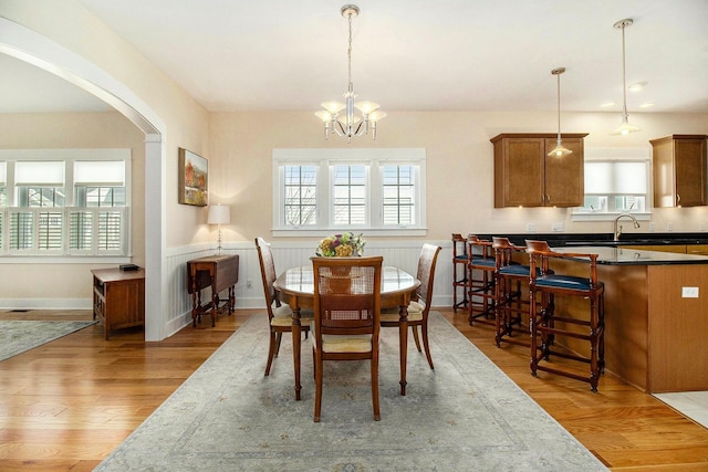 8 Georgia Ct, Pentwater, MI 49449 - dining room with arched walkways, a notable chandelier, plenty of natural light, and light wood-type flooring