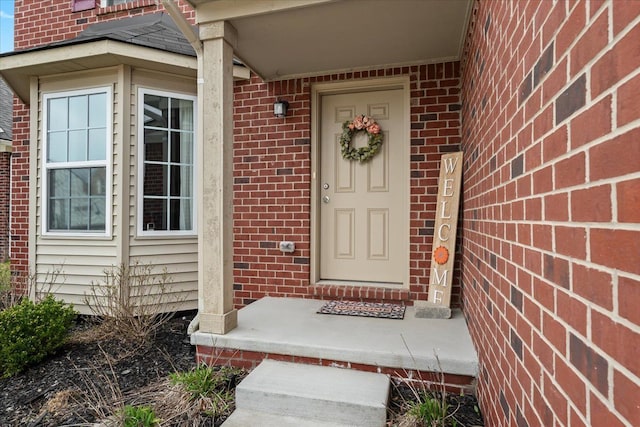 view of exterior entry featuring brick siding and covered porch